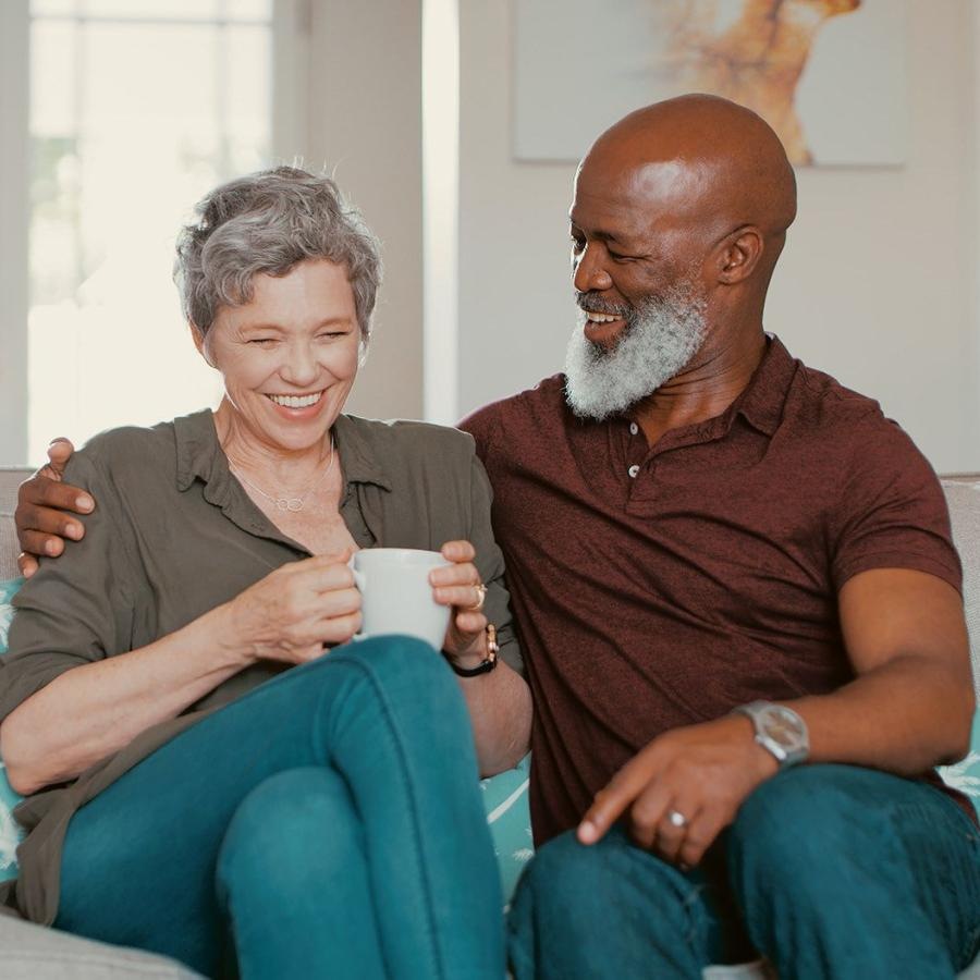 Settle into comfort at Berkley Pointe smiling, older couple, sit together on a couch